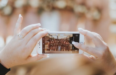 Persons hands holding a phone taking a photo of a row of bridesmaids