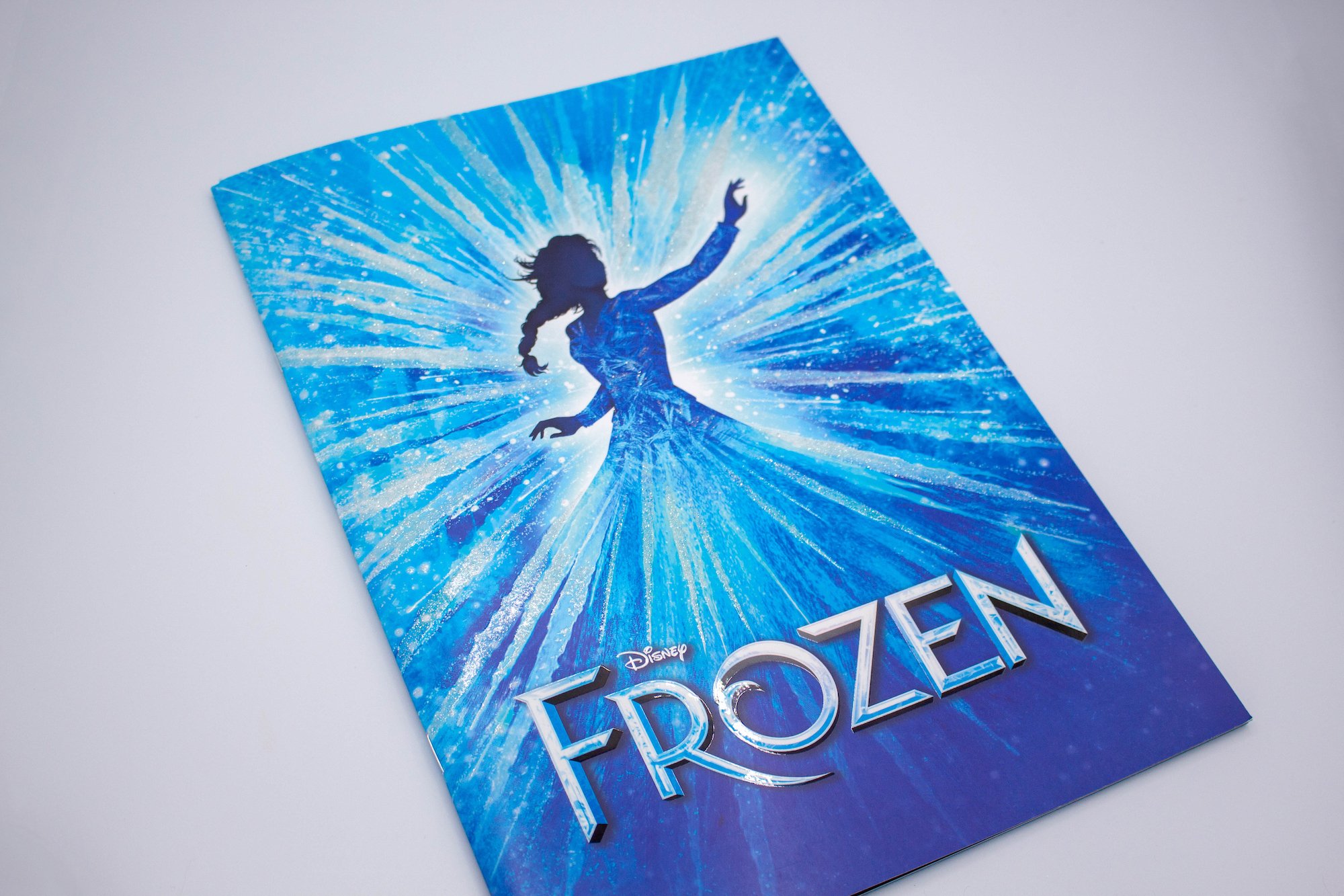 Theatre programme with a blue front cover, silhouette of a lady with glitter effect